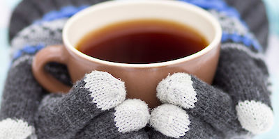 Mug of Coffee in Gloved Hands